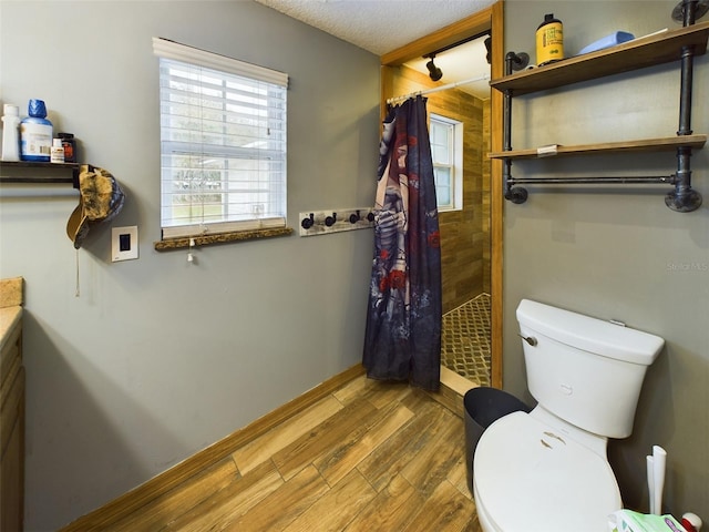 bathroom with walk in shower, vanity, a textured ceiling, wood-type flooring, and toilet