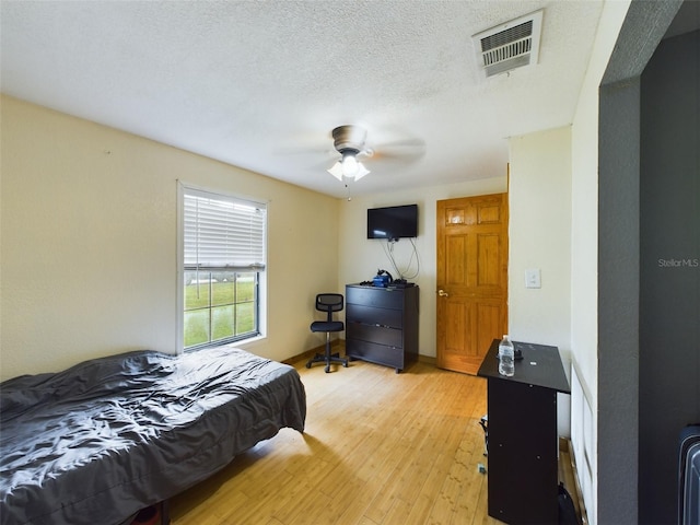 bedroom featuring ceiling fan, a textured ceiling, and light hardwood / wood-style flooring