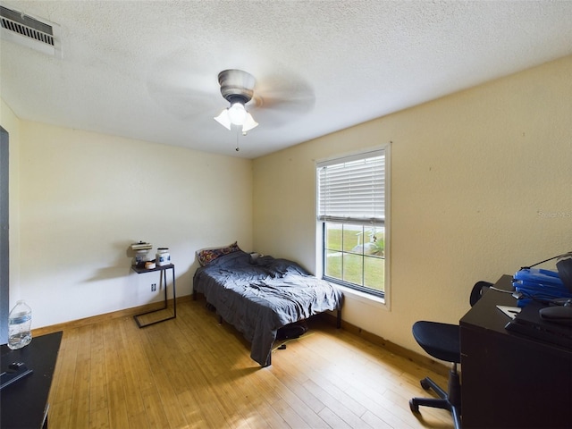 bedroom with a textured ceiling, hardwood / wood-style flooring, and ceiling fan