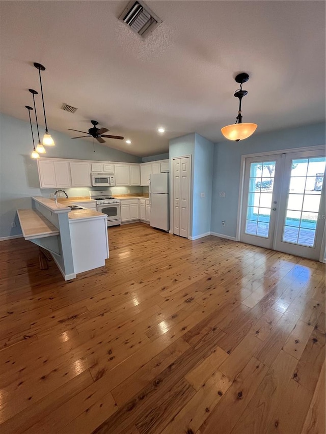 kitchen featuring kitchen peninsula, white appliances, pendant lighting, white cabinets, and light hardwood / wood-style floors