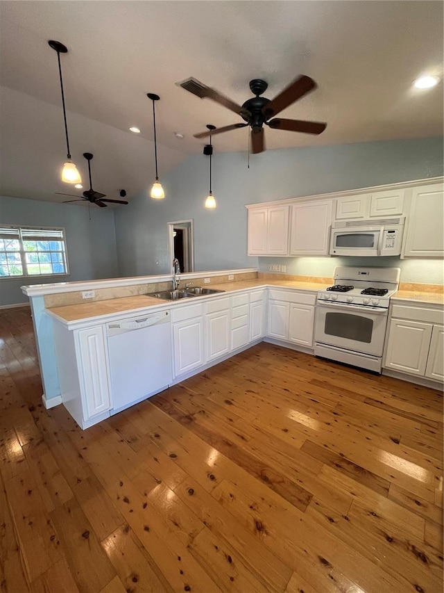 kitchen with pendant lighting, lofted ceiling, white appliances, white cabinets, and light wood-type flooring