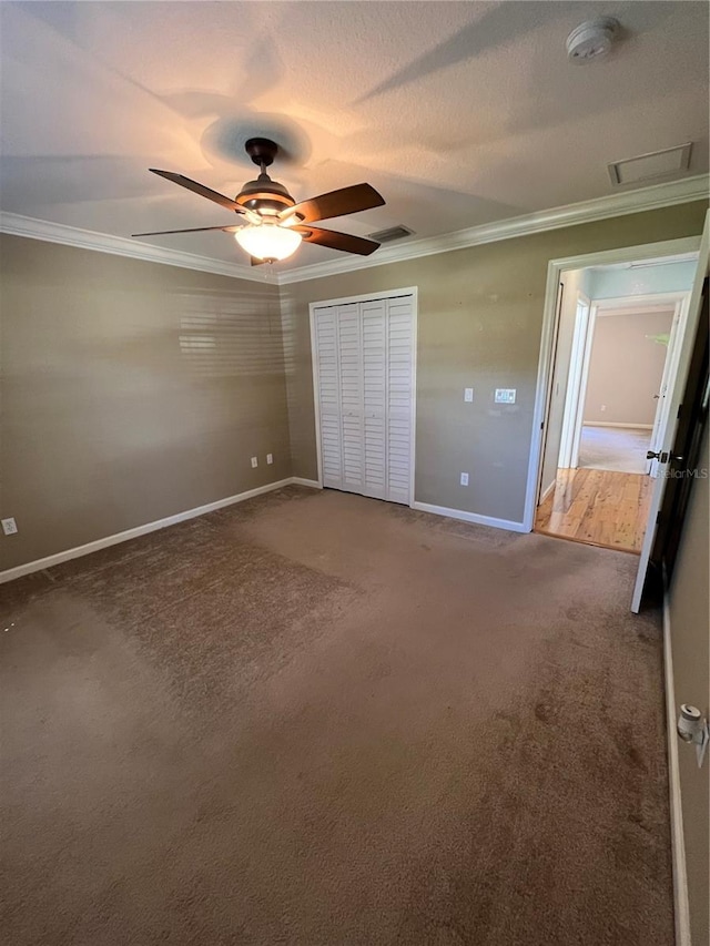 unfurnished bedroom featuring carpet flooring, ceiling fan, ornamental molding, a textured ceiling, and a closet