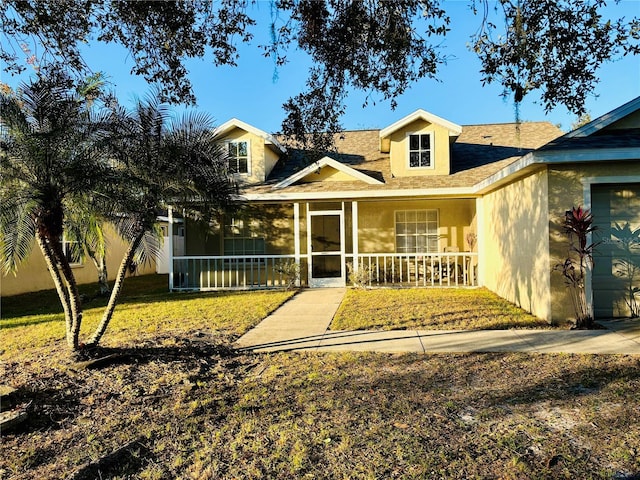 view of front of house featuring covered porch, a garage, and a front lawn