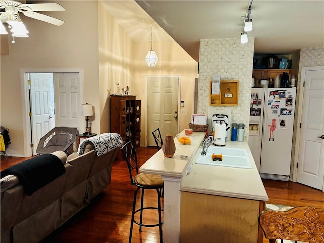 kitchen featuring sink, a kitchen breakfast bar, dark hardwood / wood-style floors, white refrigerator with ice dispenser, and pendant lighting