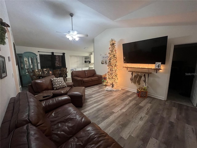 living room featuring ceiling fan, wood-type flooring, and vaulted ceiling