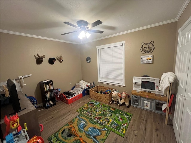 recreation room with hardwood / wood-style flooring, ceiling fan, and crown molding