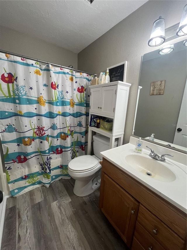 bathroom with a shower with curtain, a textured ceiling, toilet, vanity, and hardwood / wood-style flooring