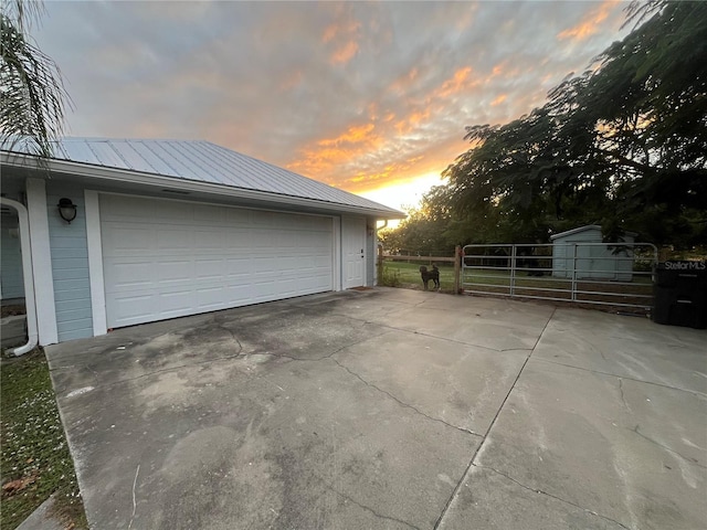 property exterior at dusk with a garage and an outbuilding