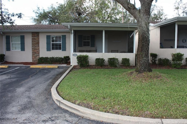 ranch-style home with a front lawn and a sunroom