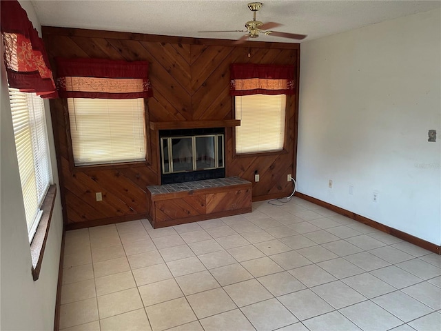 unfurnished living room with a fireplace, a textured ceiling, ceiling fan, and wood walls