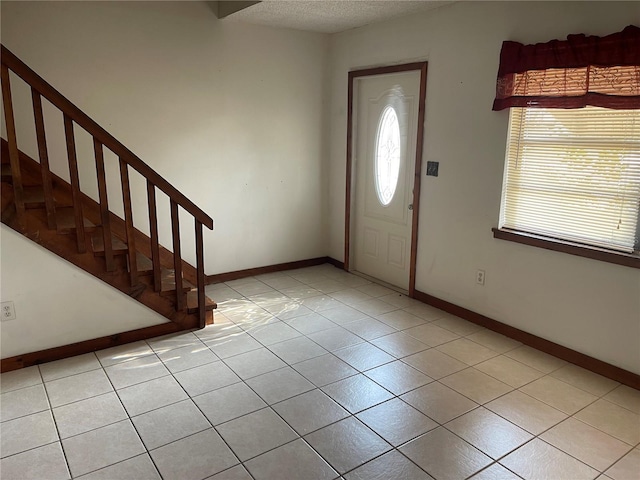 entryway with light tile patterned floors and a textured ceiling