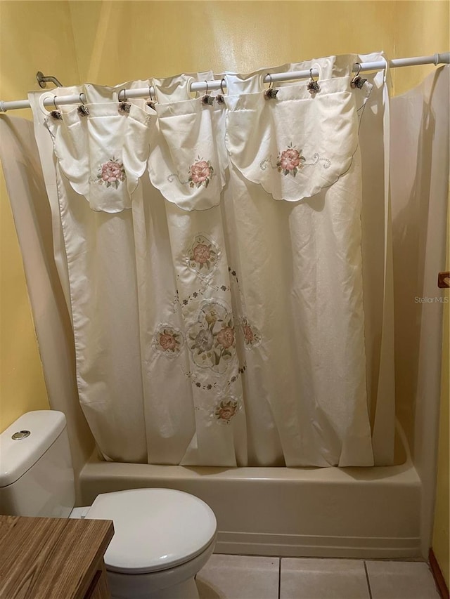 bathroom with tile patterned flooring, shower / bath combination with curtain, and toilet