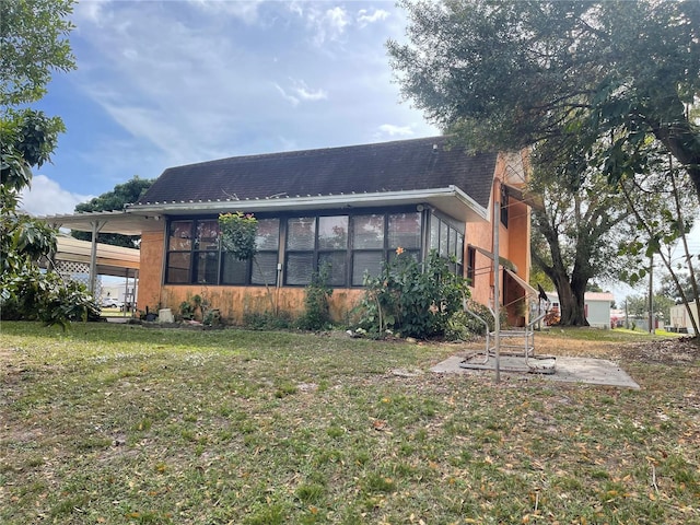 back of house featuring a lawn and a sunroom