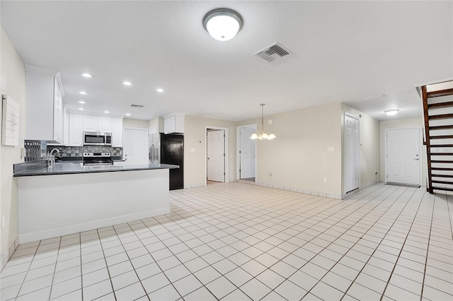 kitchen with an inviting chandelier, white cabinets, tasteful backsplash, kitchen peninsula, and stainless steel appliances