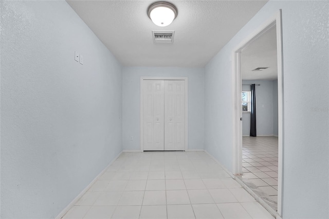 hall featuring light tile patterned flooring and a textured ceiling