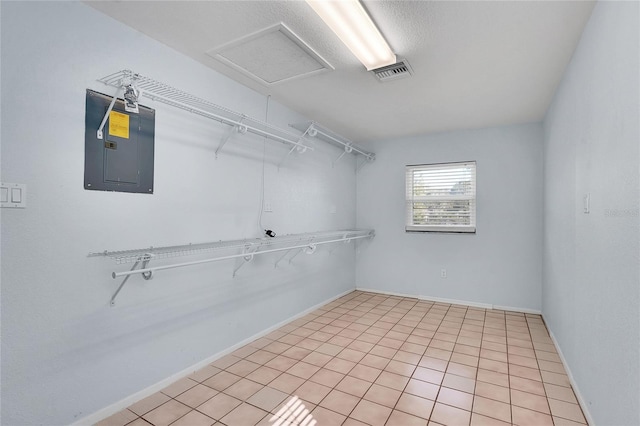 walk in closet with electric panel and light tile patterned flooring