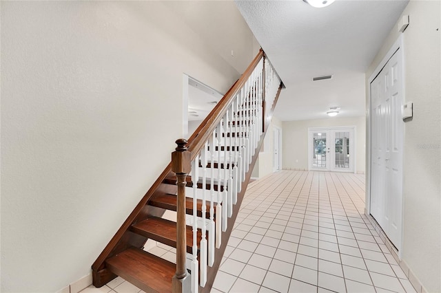 stairs featuring tile patterned floors and french doors