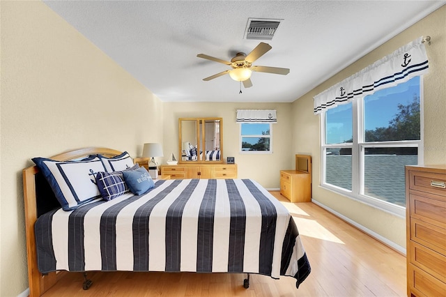 bedroom with ceiling fan, a textured ceiling, and light wood-type flooring