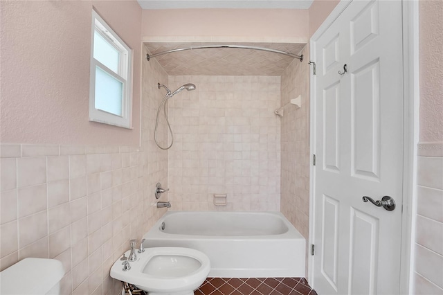 bathroom featuring tiled shower / bath, a bidet, toilet, and tile walls