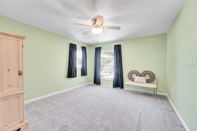 unfurnished room with a textured ceiling, ceiling fan, and light carpet