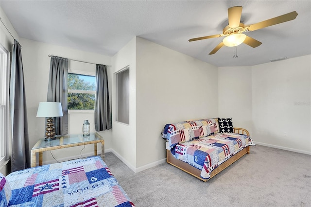 carpeted bedroom featuring ceiling fan and a textured ceiling