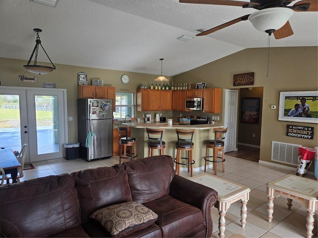 living room featuring plenty of natural light, lofted ceiling, light tile patterned floors, and french doors