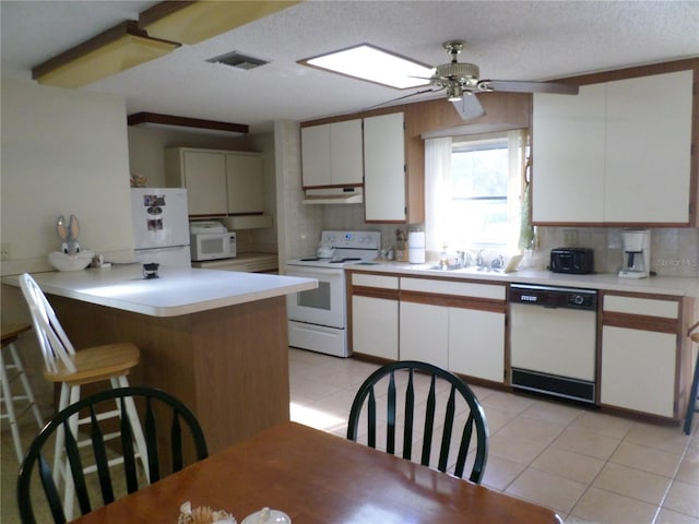 kitchen featuring backsplash, light tile patterned floors, white cabinets, white appliances, and a sink