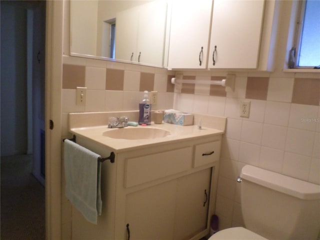 half bathroom with vanity, toilet, and tile walls