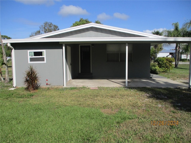 rear view of property with a carport and a lawn