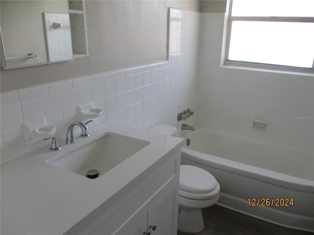 full bathroom with backsplash, vanity, tiled shower / bath combo, tile walls, and toilet