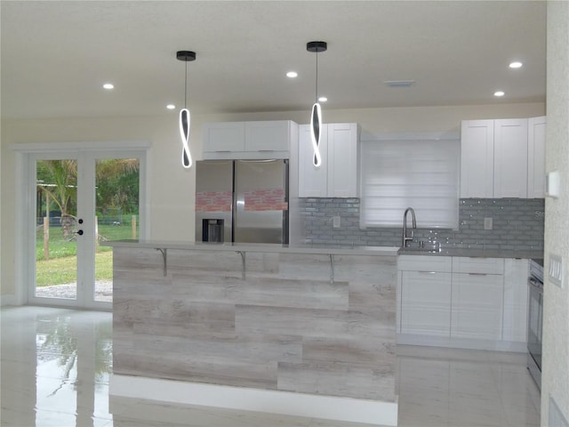 kitchen with tasteful backsplash, stainless steel fridge with ice dispenser, white cabinets, and pendant lighting