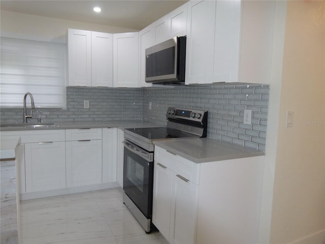 kitchen featuring white cabinets, decorative backsplash, sink, and appliances with stainless steel finishes