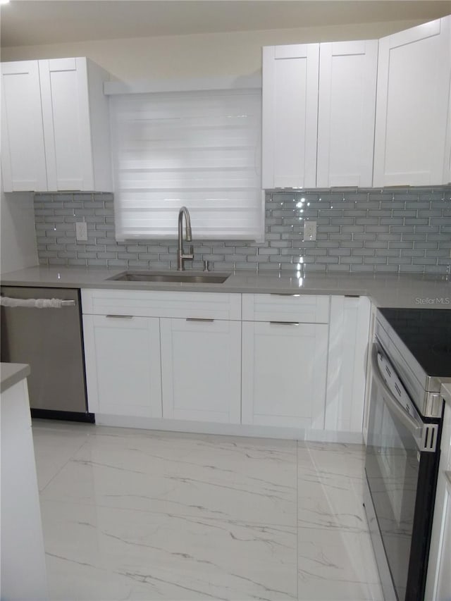 kitchen featuring appliances with stainless steel finishes, tasteful backsplash, white cabinetry, and sink