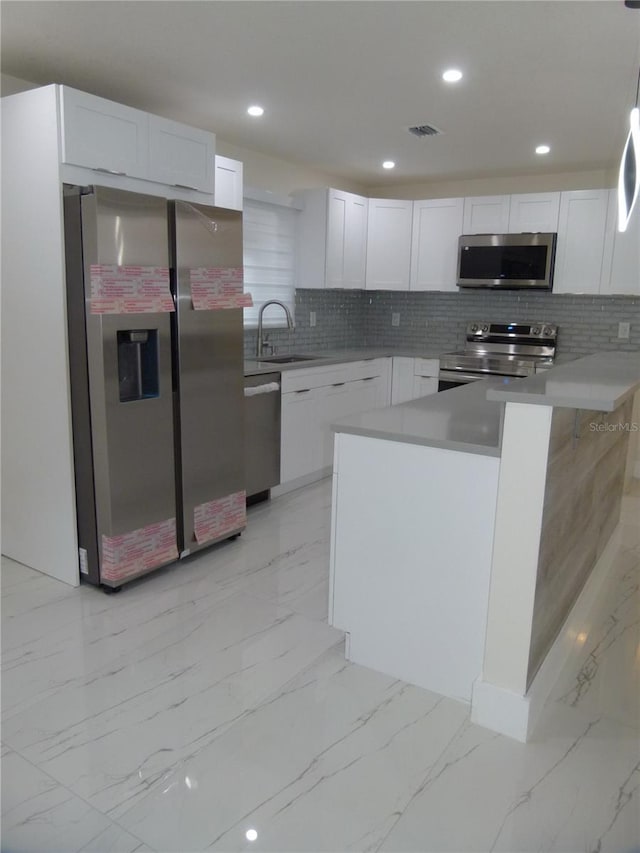 kitchen featuring white cabinets, sink, hanging light fixtures, and appliances with stainless steel finishes