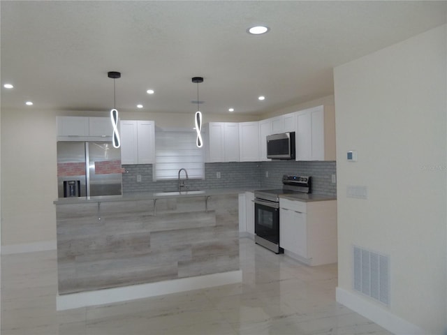 kitchen featuring white cabinets, sink, hanging light fixtures, appliances with stainless steel finishes, and tasteful backsplash