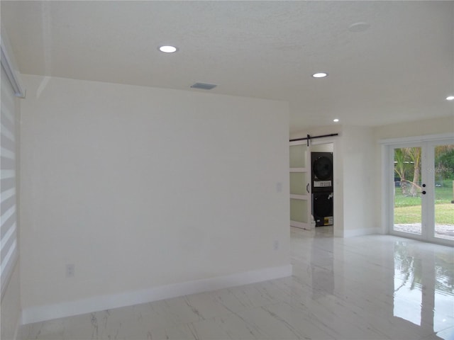 empty room featuring a barn door, french doors, and stacked washer and clothes dryer