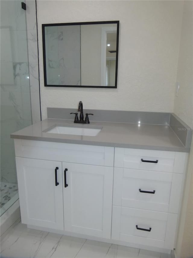 bathroom featuring a tile shower and vanity