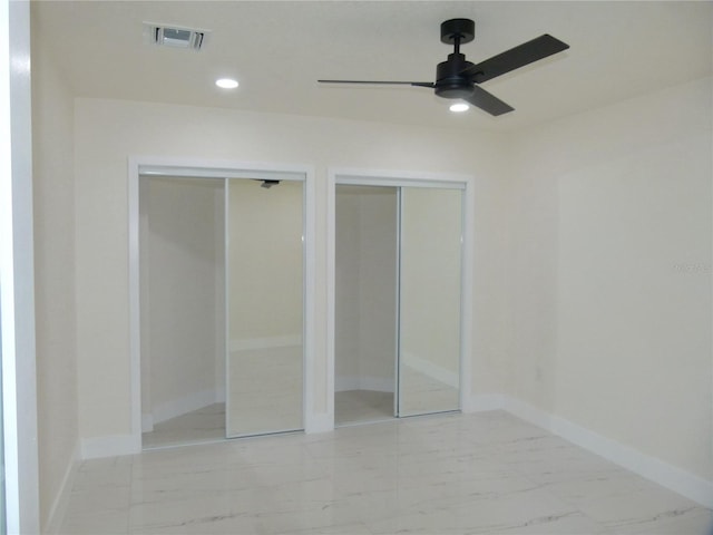 unfurnished bedroom with ceiling fan and two closets