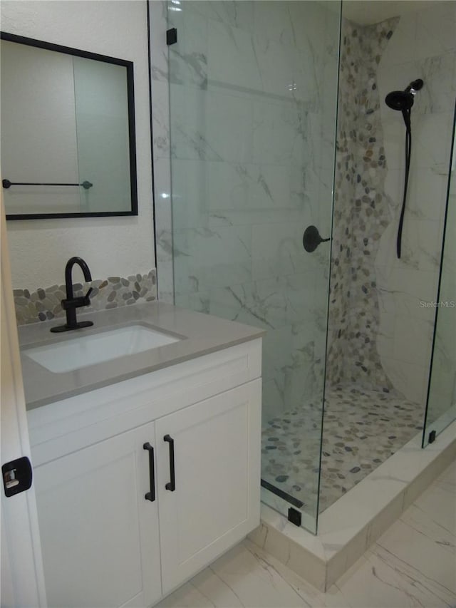 bathroom with a tile shower and vanity