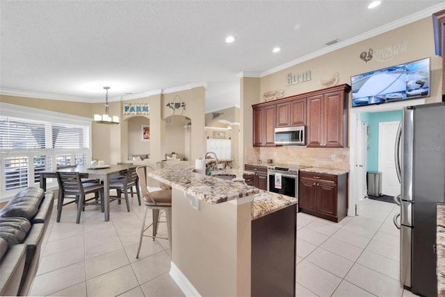 kitchen featuring a kitchen breakfast bar, sink, hanging light fixtures, light tile patterned floors, and stainless steel appliances