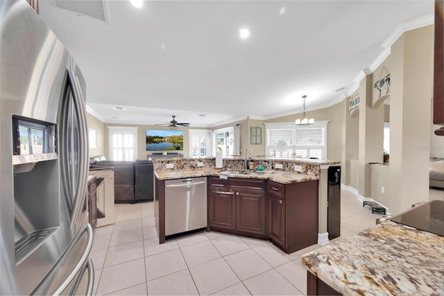 kitchen with ceiling fan with notable chandelier, sink, light stone countertops, appliances with stainless steel finishes, and decorative light fixtures