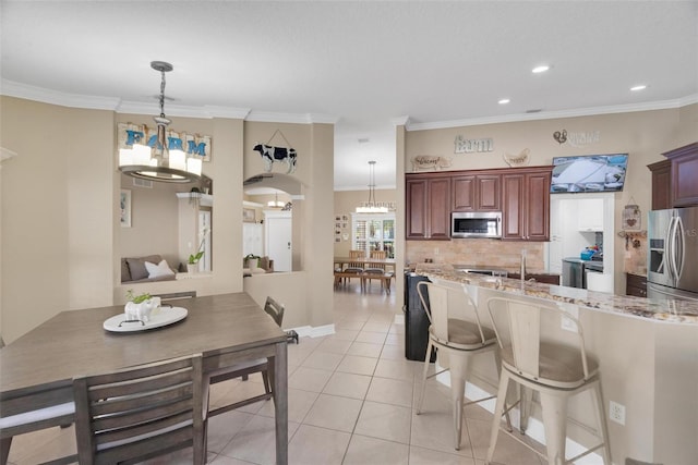 kitchen with crown molding, light tile patterned floors, hanging light fixtures, and appliances with stainless steel finishes