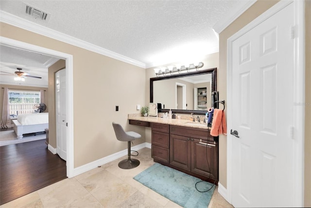 bathroom with ceiling fan, tile patterned flooring, a textured ceiling, vanity, and ornamental molding