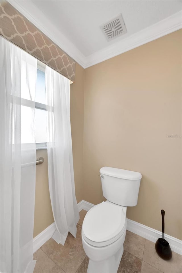 bathroom with tile patterned floors, crown molding, and toilet