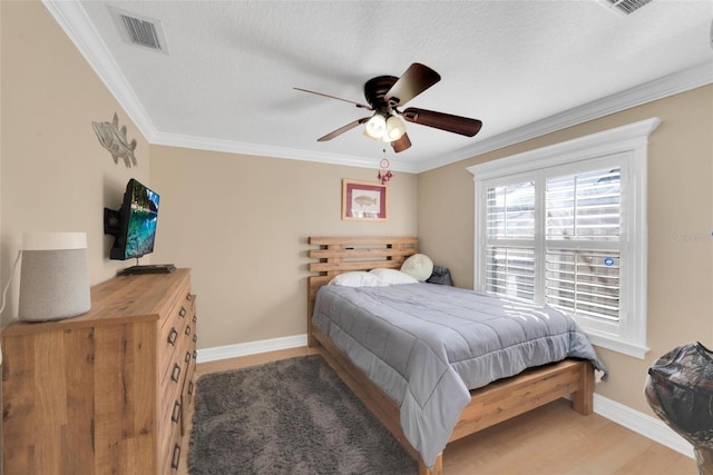 bedroom with a textured ceiling, hardwood / wood-style flooring, ceiling fan, and ornamental molding