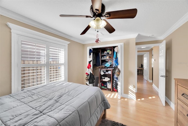 bedroom featuring ceiling fan, light hardwood / wood-style flooring, a textured ceiling, a closet, and ornamental molding