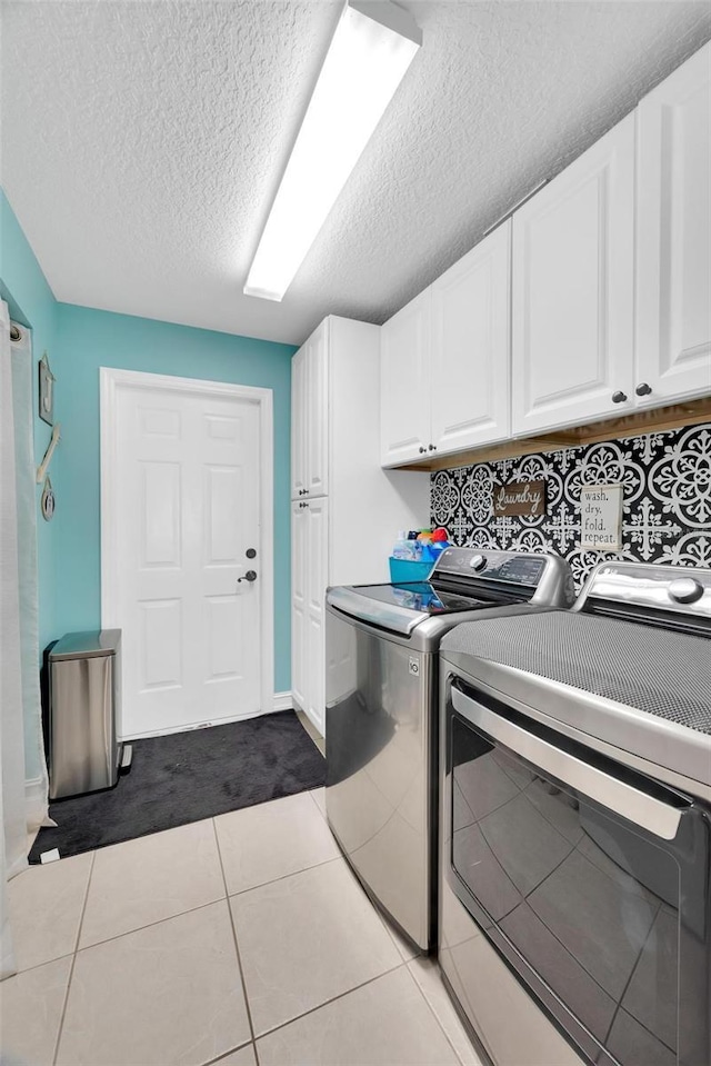 clothes washing area with light tile patterned flooring, cabinets, independent washer and dryer, and a textured ceiling