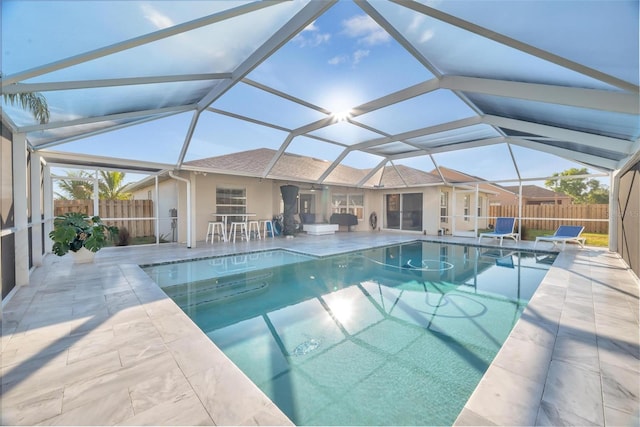 view of swimming pool with glass enclosure, ceiling fan, and a patio