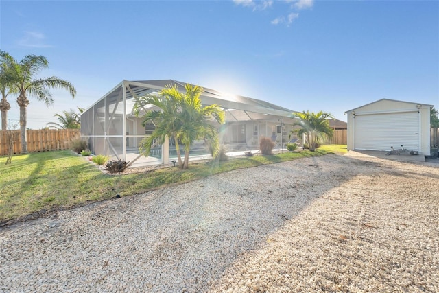 view of front of home featuring a front yard, an outdoor structure, glass enclosure, and a garage