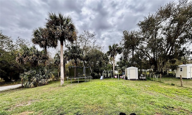 view of yard featuring a storage shed, a playground, and a trampoline